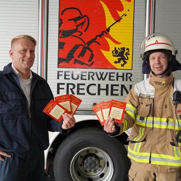 Der Löschzugführer Torsten Kremer (links) und der stellvertretende Löschzugführer Thomas Hügle präsentieren die Hinweiskarten der Freiwilligen Feuerwehr Frechen.