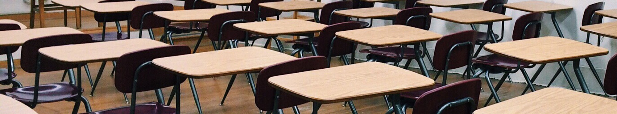 Das Symbolbild zeigt ein Klassenzimmer mit Tischen und Stühlen. Personen sind auf dem Bild keine.