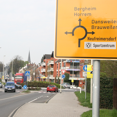 Das Foto zeigt die Aachener Straße in Frechen-Königdorf im Kreuzungsbereich zur Brauweilerstraße. Dort gibt es einen Verkehrskreisel.