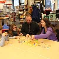 Das Foto zeigt eine Familie, die ein Brettspiel spielt