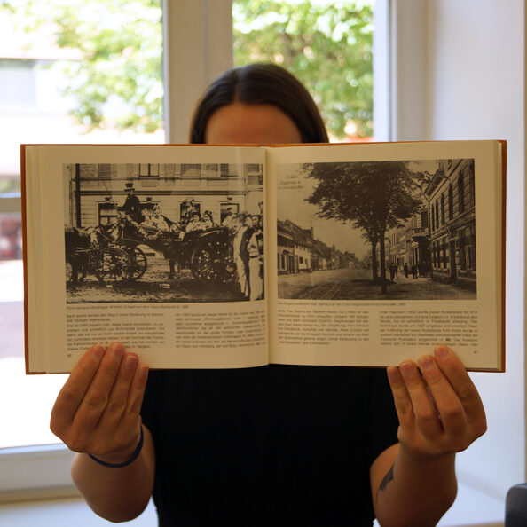 Das Bild zeigt eine Person, die ein offenes Buch in die Kamera hält.