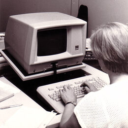 Das Bild zeigt eine Person vor einem alten Computer.