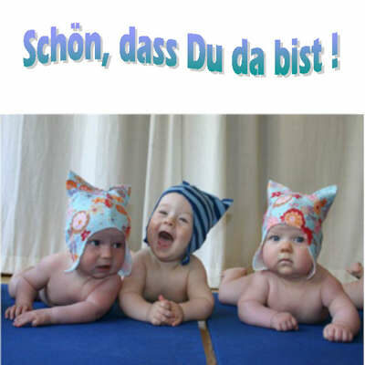 Das Symbolbild zeigt drei Säugline mit Mützen. Die Babys liegen auf blauen Matten nebeneinander.